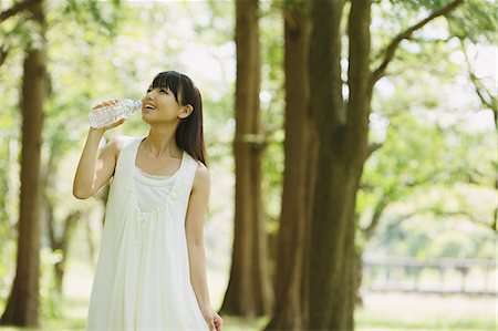 Asian woman in a white dress drinking water in the woods Stock Photo - Rights-Managed, Code: 859-06404916