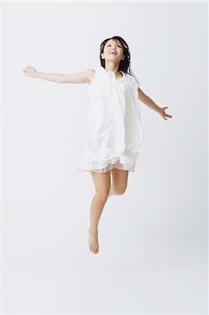 expressif (comportement) - Femme asiatique dans une robe blanche sauter Photographie de stock - Rights-Managed, Code: 859-06404918