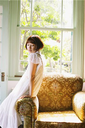 Japanese woman in a white dress leaning against a sofa Stock Photo - Rights-Managed, Code: 859-06404954