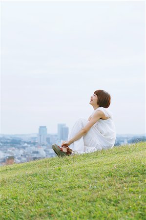 Japanese woman with short hair in a white dress sitting on the grass Stock Photo - Rights-Managed, Code: 859-06404966