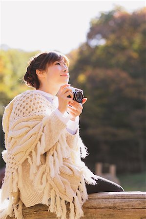 Japanese woman in a white cardigan holding a camera and looking away Stock Photo - Rights-Managed, Code: 859-06404978