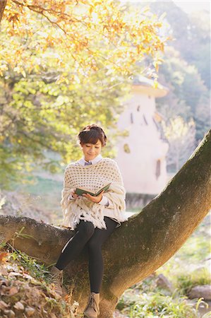 Japanese woman in a white cardigan reading a book sitting on a tree Stock Photo - Rights-Managed, Code: 859-06404985