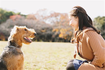 Japanese woman with long hair and a dog in a park looking at each other Stock Photo - Rights-Managed, Code: 859-06404994