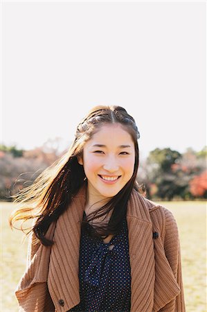 simsearch:859-06404969,k - Portrait of a Japanese woman with long hair in a park smiling at camera Fotografie stock - Rights-Managed, Codice: 859-06404996