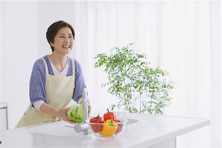 Senior adult woman washing vegetables in an open kitchen Photographie de stock - Rights-Managed, Code: 859-06469748