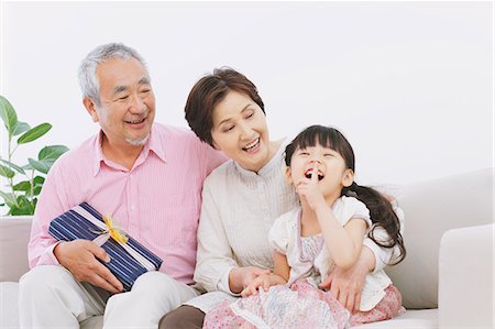 elderly couple birthday - Grandparents with a present and granddaughter laughing on the sofa Stock Photo - Rights-Managed, Code: 859-06469765