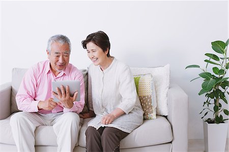 elderly couple in home - Senior adult couple sitting on a sofa with electronic tablet Photographie de stock - Rights-Managed, Code: 859-06469760