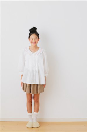 Girl in pre-adolescent age smiling at camera in front of a white wall Stock Photo - Rights-Managed, Code: 859-06469849