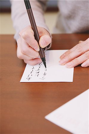 Close up of senior adult woman hands writing Japanese New Year postcard Stock Photo - Rights-Managed, Code: 859-06470207