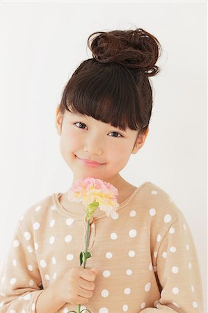 fossetta - Young girl with flower smiling at camera Fotografie stock - Rights-Managed, Codice: 859-06537991