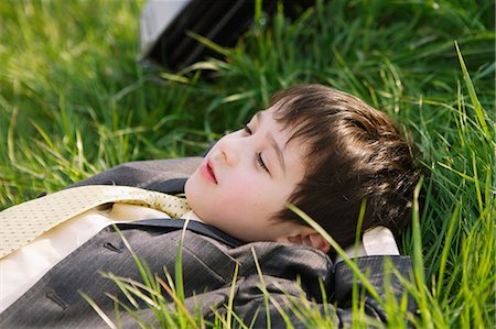 spring landscape kids - Young boy in school uniform laying on grassland Stock Photo - Rights-Managed, Code: 859-06808448