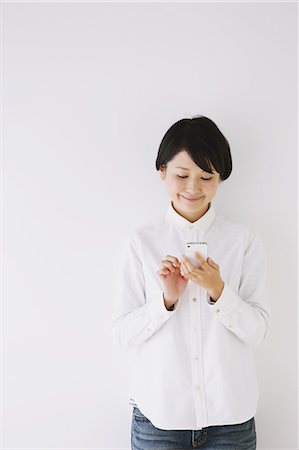 Young woman in a white shirt using smart phone Foto de stock - Con derechos protegidos, Código: 859-06824634