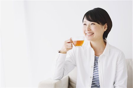 simsearch:859-03600705,k - Young woman in a white shirt drinking tea Stockbilder - Lizenzpflichtiges, Bildnummer: 859-06824648