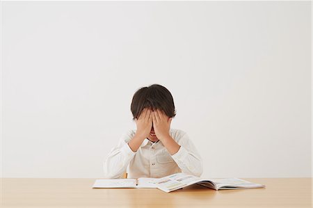 embarrassing - Young boy doing his homework on wooden desk Stock Photo - Rights-Managed, Code: 859-07710987