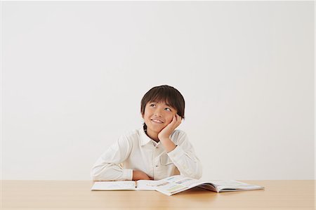 pondering in a university classroom - Young boy doing his homework on wooden desk Stock Photo - Rights-Managed, Code: 859-07710981