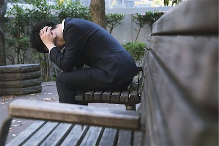 deprimido - Desperate Japanese young businessman in a suit sitting on a bench in a park Foto de stock - Con derechos protegidos, Código: 859-07711097