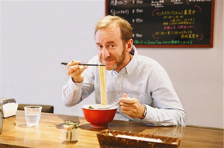 simsearch:859-07150143,k - Caucasian man with beard eating ramen noodles Foto de stock - Con derechos protegidos, Código: 859-08173133