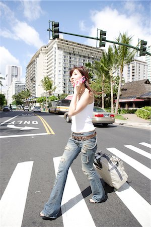 Young woman with carry-on luggage crossing a road Stock Photo - Rights-Managed, Code: 859-03036004