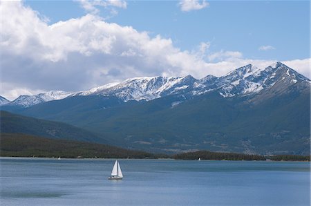 simsearch:859-03037551,k - Bateau à voile dans l'eau du lac avec les montagnes en arrière-plan Photographie de stock - Rights-Managed, Code: 859-03037549