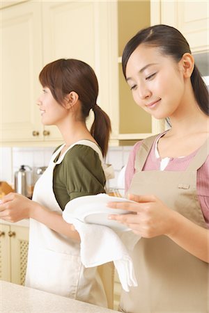 Side view of young women wiping plates in kitchen Stock Photo - Rights-Managed, Code: 859-03038415