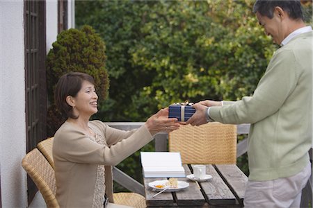 senior couple candid outdoors - Side view of a man giving gift to woman Stock Photo - Rights-Managed, Code: 859-03038539