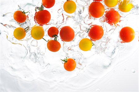 Cherry Tomatoes Splashing In To Water Foto de stock - Direito Controlado, Número: 859-03598637