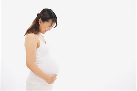 pregnant asian belly - Pregnant Woman Smiling while Touching her Belly Stock Photo - Rights-Managed, Code: 859-03600077