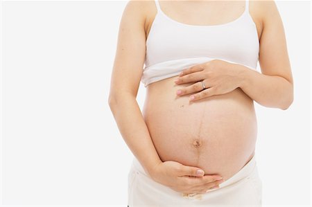 pregnant woman standing white background - Pregnant Woman Standing Holding her Abdomen Stock Photo - Rights-Managed, Code: 859-03600085