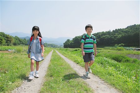 Amis en passant par Rural sentier sur le chemin de l'école Photographie de stock - Rights-Managed, Code: 859-03755133