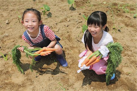 Girls Sitting At Muddy Field With Carrot Bunch Foto de stock - Con derechos protegidos, Código: 859-03755192