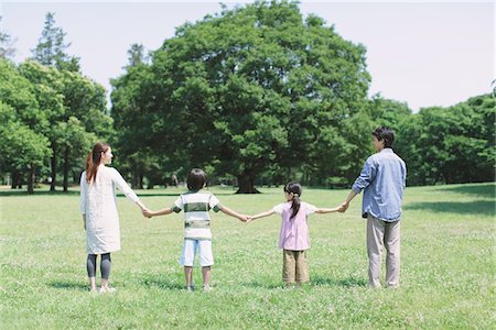 father mother kid holding hands in park - Family Standing In a Park Stock Photo - Rights-Managed, Code: 859-03755315