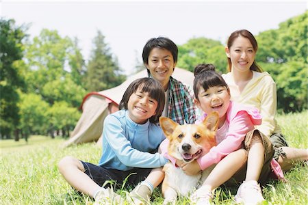 family on picnic with dog - Famille bénéficiant de pique-nique dans un champ avec animal de compagnie Photographie de stock - Rights-Managed, Code: 859-03755391