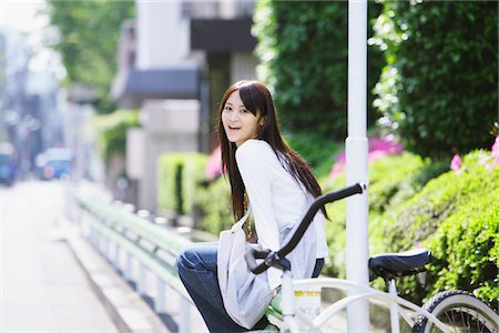 simsearch:859-03782190,k - Jeune femme assise sur la bicyclette et souriant à la caméra Photographie de stock - Rights-Managed, Code: 859-03782131