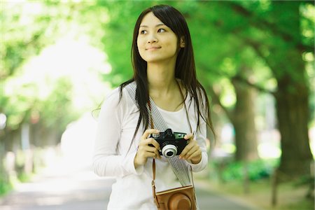 simsearch:859-03782200,k - Young Woman Standing Holding Digitalkamera Stockbilder - Lizenzpflichtiges, Bildnummer: 859-03782177