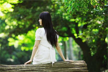 Young Woman Sitting on Tree Trunk Stock Photo - Rights-Managed, Code: 859-03782204