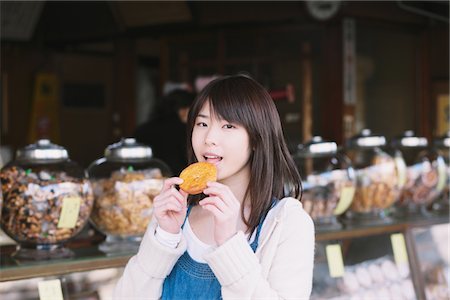 Teenage Girl Eating Cookie At Bakery Shop Stock Photo - Rights-Managed, Code: 859-03839961