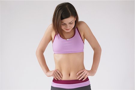 female body waist - Young Woman Looking Down Hands On Waist Stock Photo - Rights-Managed, Code: 859-03840011