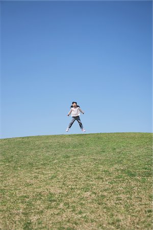 Girl Jumping on Grass hill Stock Photo - Rights-Managed, Code: 859-03840856