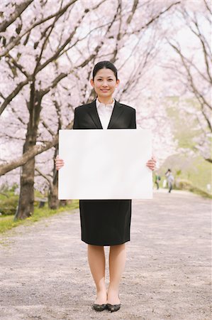 simsearch:859-03885009,k - Femme d'affaires détenant un tableau blanc avec des fleurs de la cerise en arrière-plan Photographie de stock - Rights-Managed, Code: 859-03884974