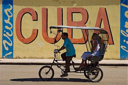 A Ricksaw passes a Viva Cuba sign,Havana,Cuba Foto de stock - Con derechos protegidos, Código: 851-02959374