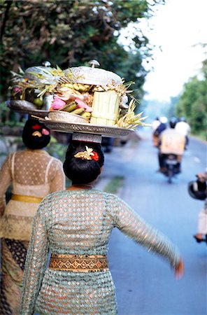 simsearch:851-02960358,k - Woman ( women ) in embroidered dress with temple offerings walking down a road with motorcyclists in the distance . Ubud,Bali,Indonesia . Foto de stock - Con derechos protegidos, Código: 851-02960217