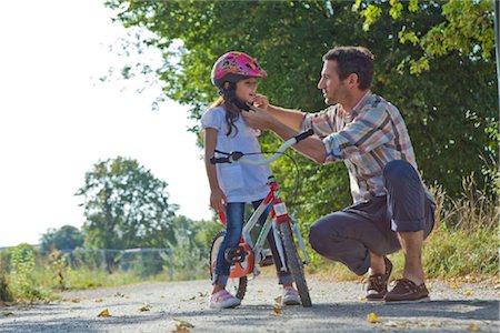 family on bikes - Père fermant le casque de sa fille sur une moto Photographie de stock - Rights-Managed, Code: 853-05840935