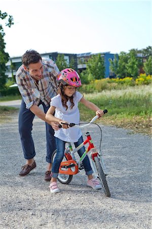family bicycling - Father holding daughter on bike outdoors Foto de stock - Con derechos protegidos, Código: 853-05840943