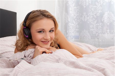 simsearch:853-06120564,k - Young woman listening to music in bed Fotografie stock - Rights-Managed, Codice: 853-06120544