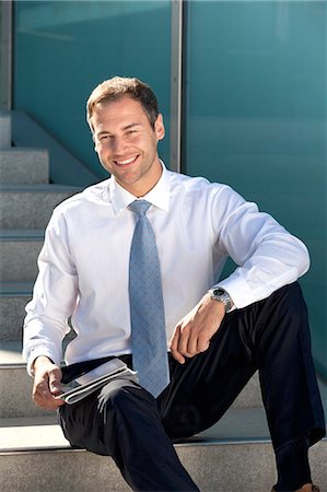 reading newspaper - Smiling businessman sitting with tablet PC and newspaper on stairs Stock Photo - Rights-Managed, Code: 853-06441632