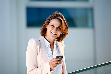 f1online - Femme d'affaires souriant avec un téléphone cellulaire, portrait Photographie de stock - Rights-Managed, Code: 853-06441653