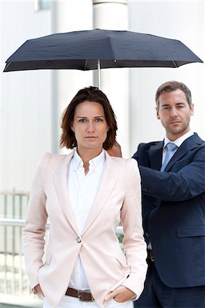 serious male looking at camera - Businessman holding umbrella above businesswoman Stock Photo - Rights-Managed, Code: 853-06441697