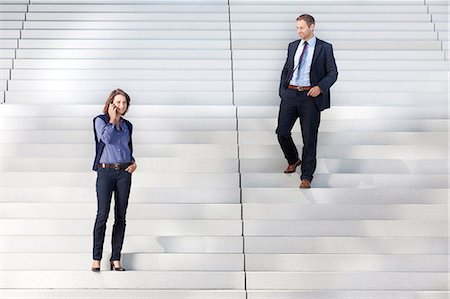 Homme d'affaires, femme d'affaires en regardant sur le téléphone dans les escaliers Photographie de stock - Rights-Managed, Code: 853-06441722