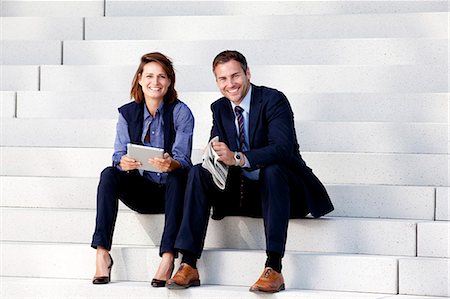 Businessman and businesswoman with tablet PC and newspaper on stairs Stock Photo - Rights-Managed, Code: 853-06441732