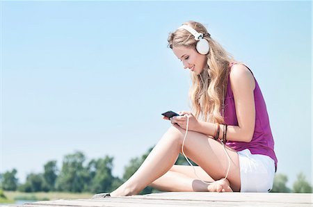 dock side view - Blond young woman with headphones on a jetty at a lake Stock Photo - Rights-Managed, Code: 853-06442067